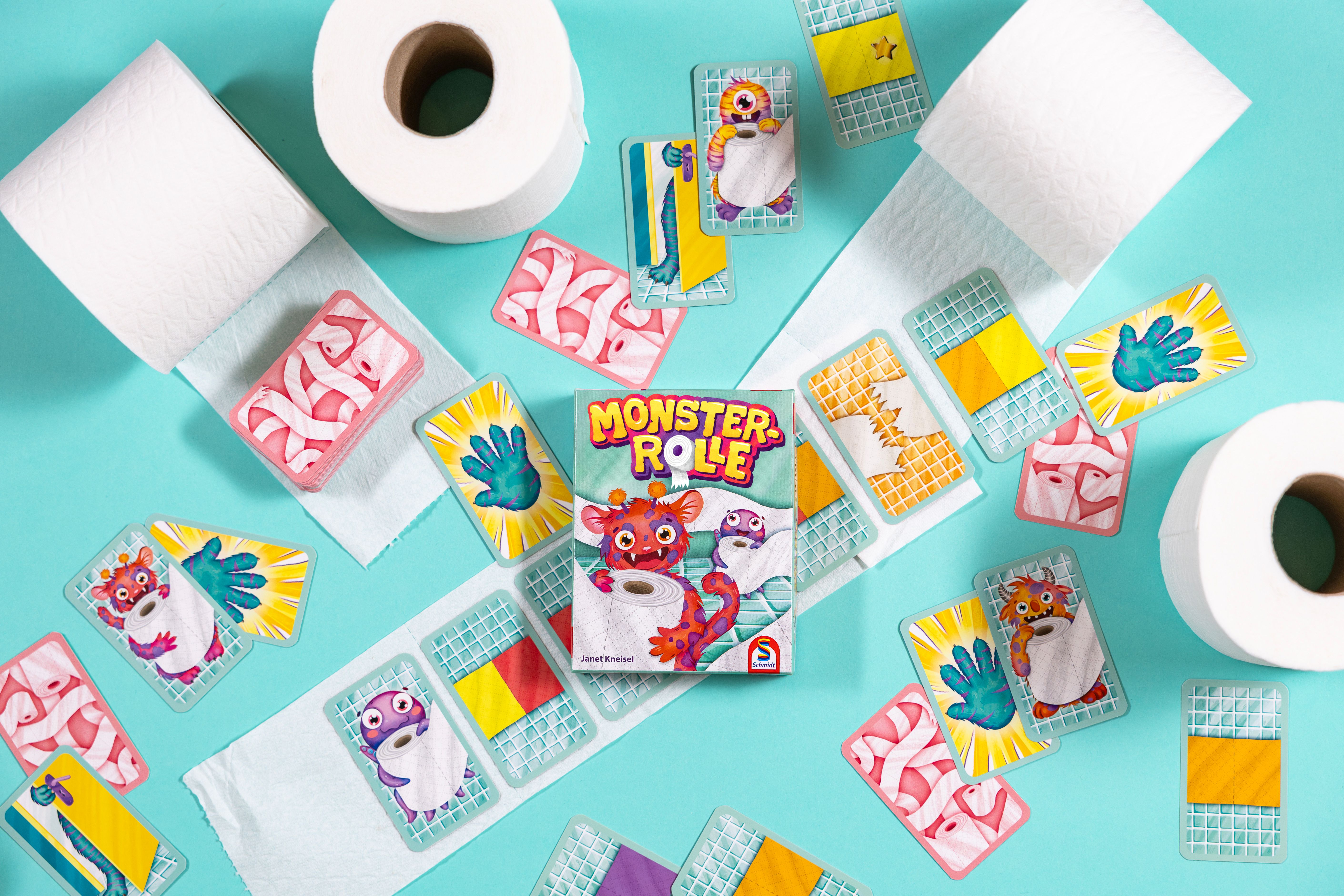 Buntes Kartenspiel Monsterrolle mit Monstern, Klopapierrollen und Spielkarten auf hellblauem Hintergrund.